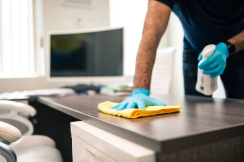 Man disinfecting an office desk Man disinfecting an office desk